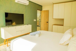 Habitació d'hotel amb llit, televisió sobre un suport, armari i bany visible a través d'una porta oberta.