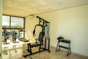 Un gimnàs amb equip d'exercici, una cinta de córrer i una pilona per a peses.