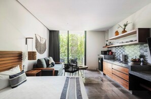 A modern hotel room with a bed, seating area, and kitchenette. - Elegante Estudio en Av. Coba (Tulum)