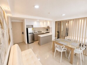 A modern kitchen with a refrigerator, stove, and sink. There is a dining area with a table and chairs. - Palmar Apartment – Near Buenavista by SOHO – 33A (Barranquilla)