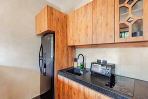 A modern kitchen with wooden cabinets, a stainless steel refrigerator, a sink, and a built-in toaster. - Selva Tulum · Private pool and rooftop · 1BR (Tulum)