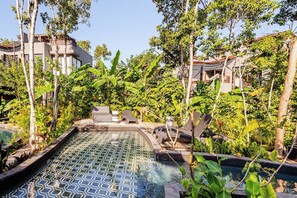 A pool area with lounge chairs and a tiled deck surrounded by tropical vegetation. - Selva Tulum · Private pool and rooftop · 1BR (Tulum)