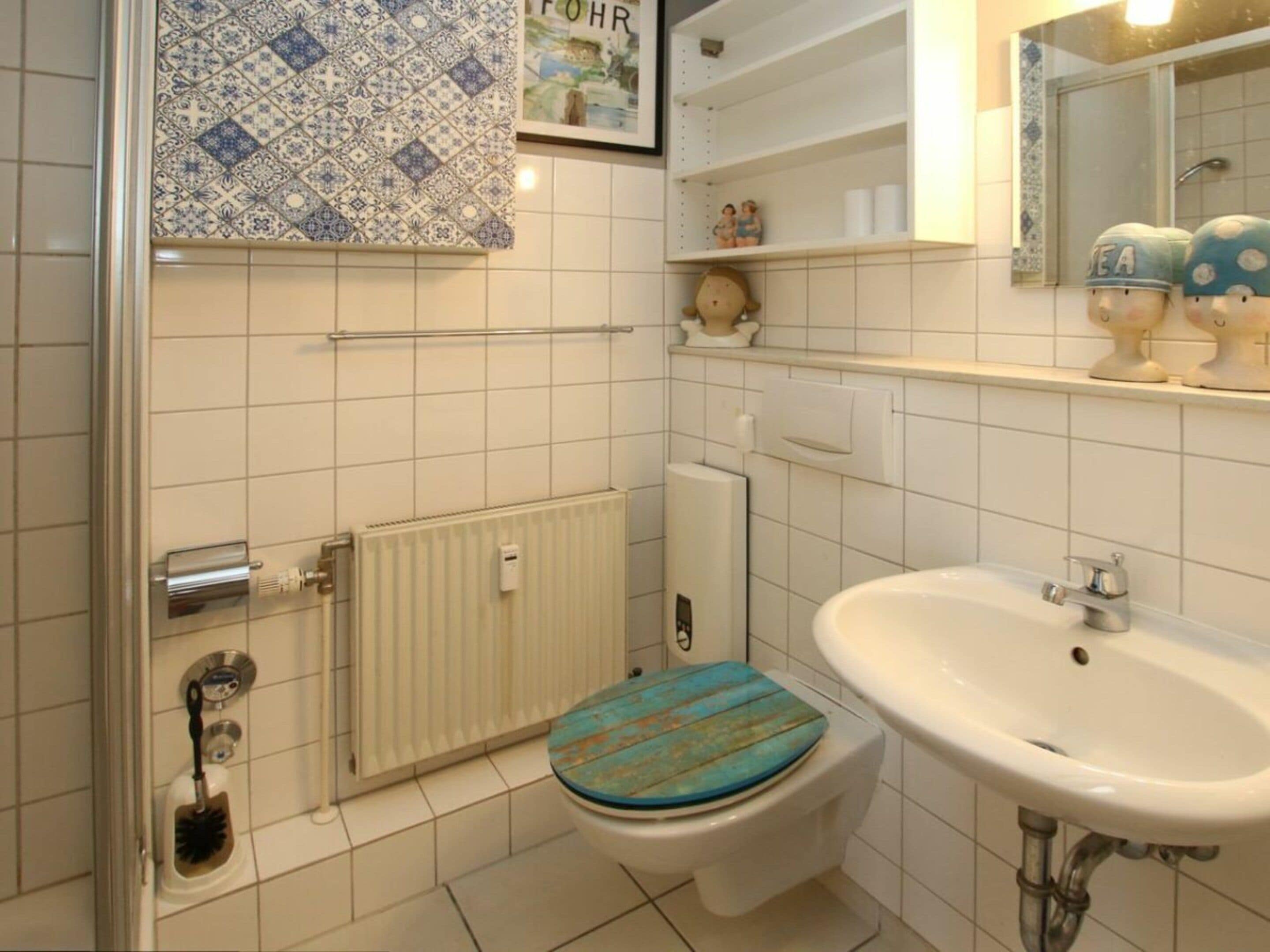 Un baño con inodoro, lavabo, ducha y radiador.