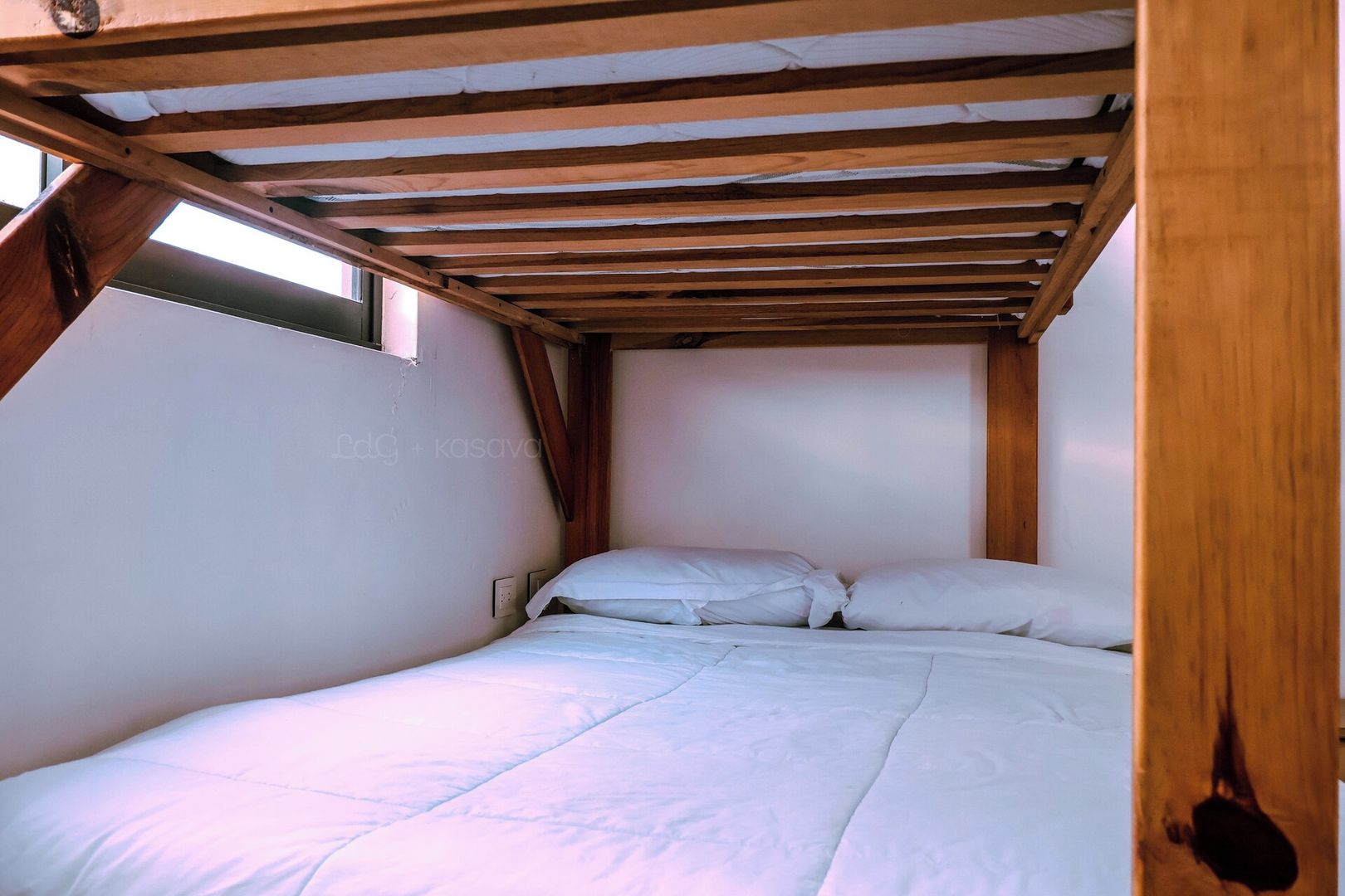 A small, single-bed room with a sloped ceiling and wooden beams.