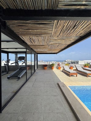 A rooftop terrace with a pool, exercise equipment, and potted plants. - Rooftop Pool 2BR · 2 min to 5th Ave and Beach (Playa del Carmen)