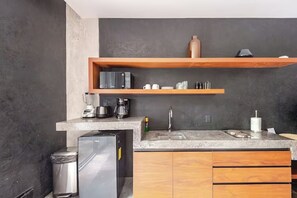 A modern kitchen with a granite countertop, stainless steel appliances, wooden cabinets, and a built-in oven. - Premium studio · Private immersion · Gym and Sauna (Tulum)