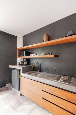 A modern kitchen with a granite countertop, wooden cabinets, a built-in oven, and a microwave. - Premium studio · Private immersion · Gym and Sauna (Tulum)