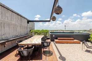 A rooftop terrace with a wooden table and chairs, a pool, and a view of the city skyline. - Premium studio · Private immersion · Gym and Sauna (Tulum)