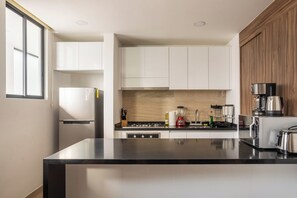 A modern kitchen with white cabinets, a black countertop, and stainless steel appliances. - 3BR Favorite · Private Pool + Cenote · Tulum (Tulum)