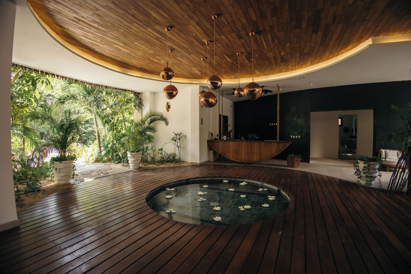 A modern interior with a wooden ceiling, a reception desk, and a glass water feature.