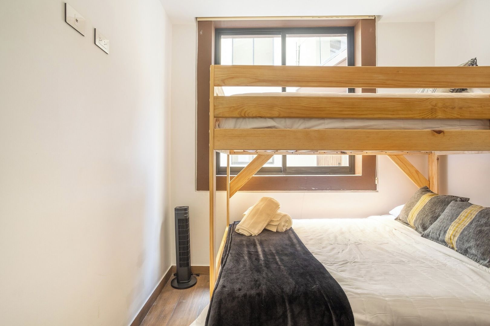 Ein Schlafraum mit Etagenbett, Fenster, Heizung und Steckdose.