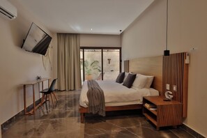 A modern bedroom with a bed, a desk, a chair, a TV mounted on the wall, and a window with curtains. - 3BR Favorite · Private Pool + Cenote · Tulum (Tulum)