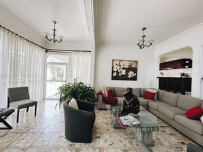 A spacious living room with a large window, a sofa set, a coffee table, and a painting on the wall. - Hot Pool with Solar Panels! (Jiutepec)