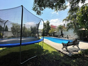 A backyard with a trampoline, a swimming pool, and a bench. - Hot Pool with Solar Panels! (Jiutepec)