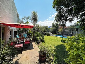 A patio area with a red umbrella, outdoor furniture, and a swimming pool. - Hot Pool with Solar Panels! (Jiutepec)