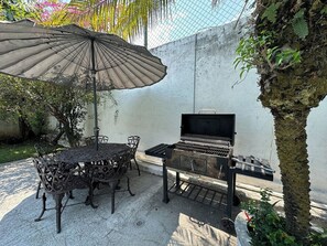 An outdoor patio with a grill, a table with chairs, and an umbrella. - Hot Pool with Solar Panels! (Jiutepec)