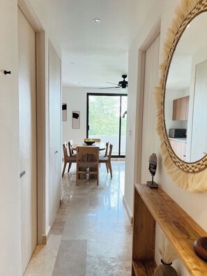 A modern interior with a dining area, a ceiling fan, and a large mirror. - PH con alberca privada (Tulum)