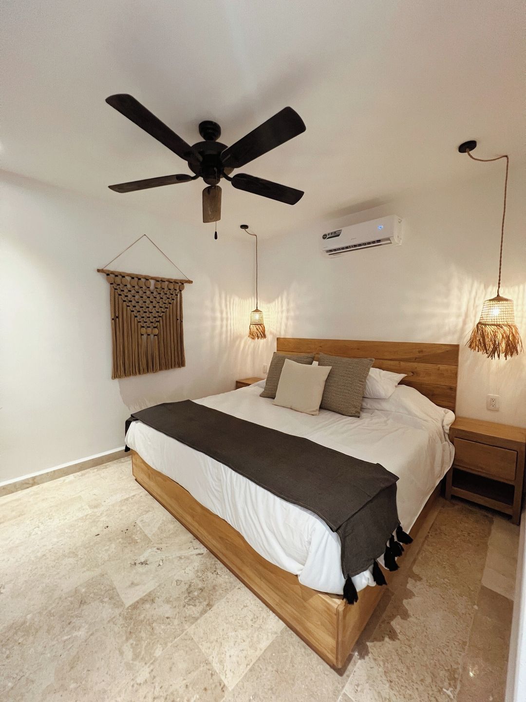Une chambre à coucher comprenant un lit, un ventilateur de plafond, un appareil de climatisation et un luminaire suspendu.