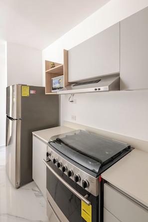 A modern kitchen with a stainless steel refrigerator, a built-in oven, and a microwave.