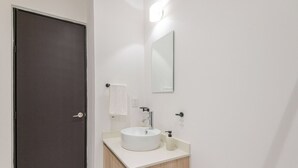 Ein Badezimmer mit einer dunklen Tür, einem weißen Waschbecken, einem Spiegel und einem Handtuch an der Wand.