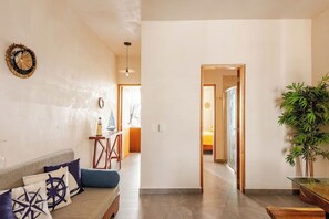 A living room with a sofa, a small table, and a potted plant. - Modern Apartment with Jacuzzi (Tulum)