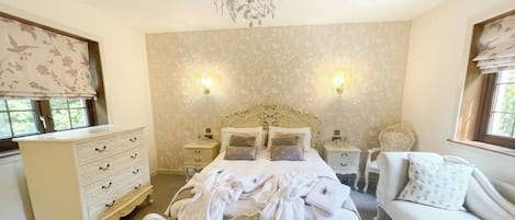 Un dormitorio con cama, mesitas de noche, cómoda y sofá.