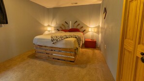 Ein Schlafzimmer mit einem Bett, Nachttischlampen, einem Holz-Kopfstück und einer Tür.
