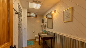 Ein Badezimmer mit Holztür, Toilette, Waschbecken mit Spiegel und Handtuchhalter.