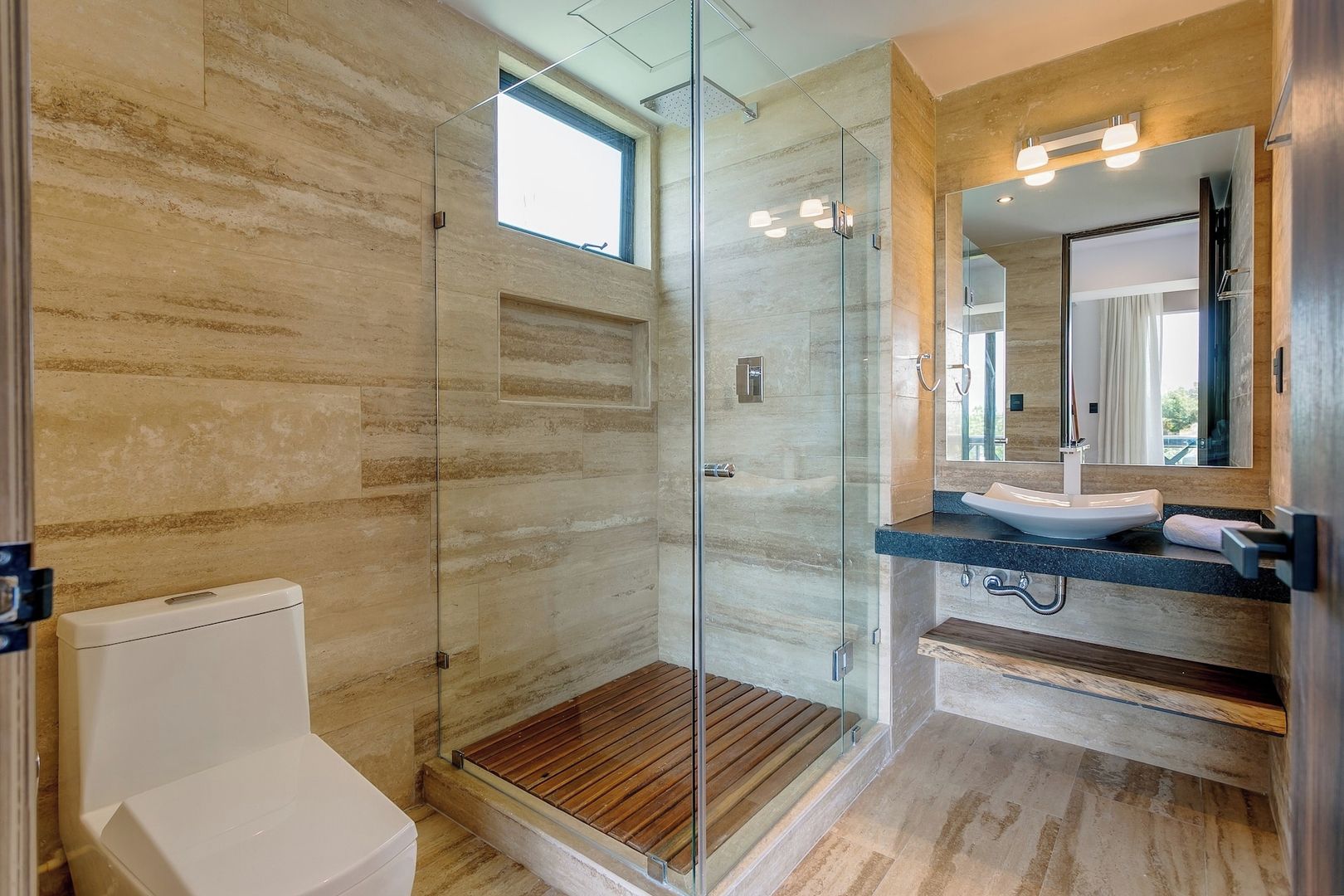 A modern bathroom with a glass-enclosed shower, a white toilet, and a sink with a mirror above it.
