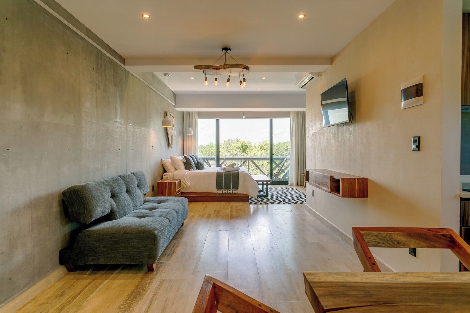Ein modernes Schlafzimmer mit einem großen Bett, einer Couch, einem Fernseher und einem Balkon mit Blick.