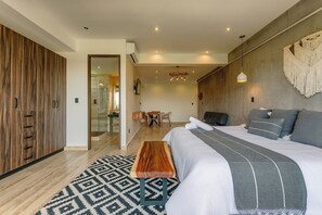 Ein modernes Schlafzimmer mit einem großen Bett, einem Holzschrank, einer Glasdusche und einem Essbereich.