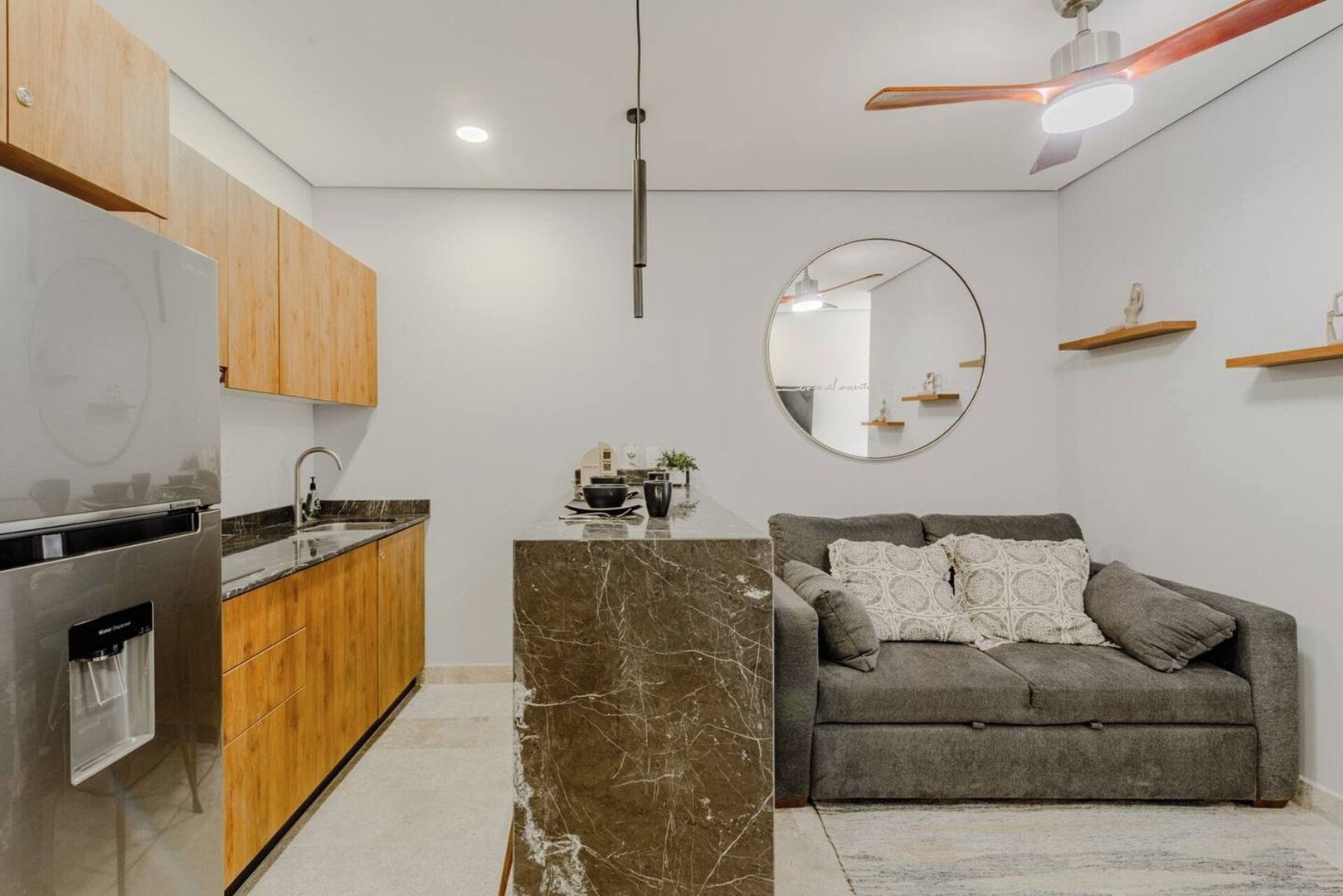 A modern kitchen with a marble island, wooden cabinets, and a built-in refrigerator.