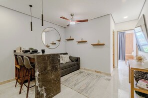 Un saló modern amb un sofà, zona de menjador i un ventilador de sostre.