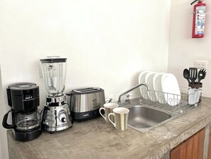 A kitchen with a coffee maker, blender, toaster, and a sink with dish racks. - Downtown Tulum Cozy 1bd Apartment (Tulum)