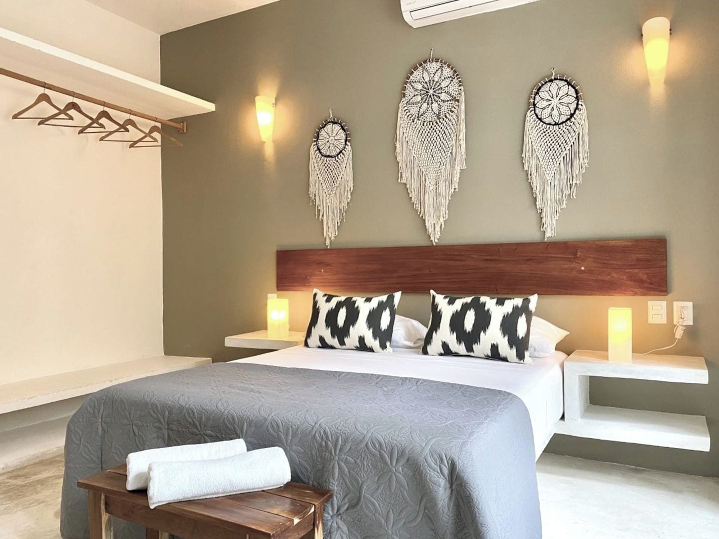 A hotel room with a bed, bedside tables, a bench, and wall decorations.