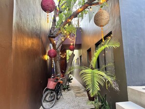 A narrow alleyway with a bicycle, decorative hanging items, and potted plants. - Downtown Tulum Cozy 1bd Apartment (Tulum)