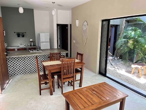 A modern kitchen with a dining area, a small outdoor seating area, and a view of a garden. - Downtown Tulum Cozy 1bd Apartment (Tulum)