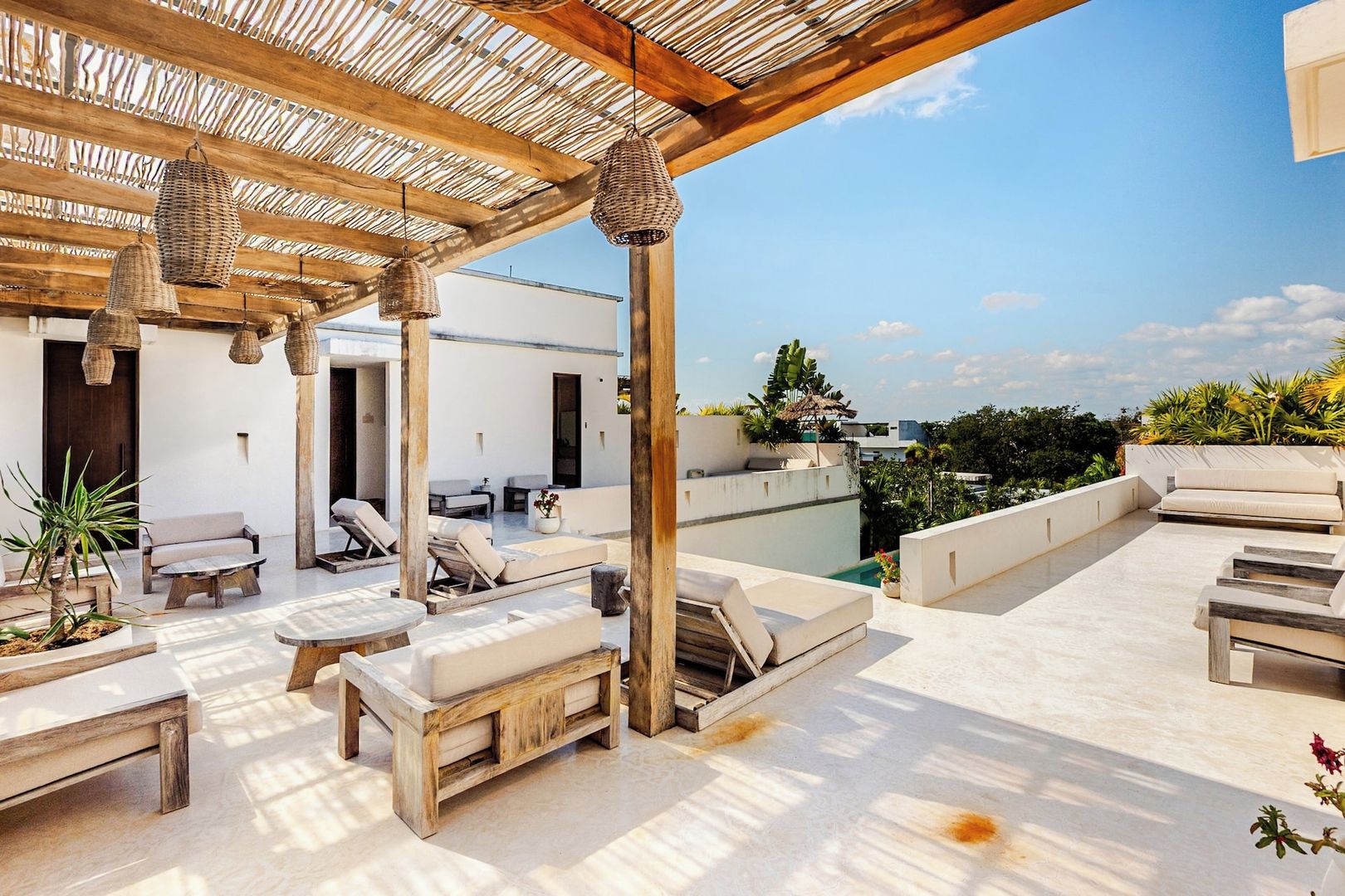A rooftop terrace with outdoor seating, a pergola, and a view of the city skyline.