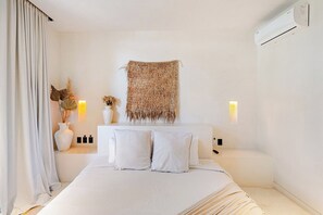 Ein Hotelzimmer mit Bett, Nachttischen, einer fest installierten Klimaanlage und einem dekorativen Wandteppich.