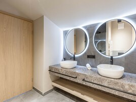 Un baño moderno con dos lavamanos, una puerta de madera y una encimera de mármol.