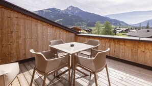 Una terraza de madera con una mesa y sillas, con vistas a un paisaje montañoso.