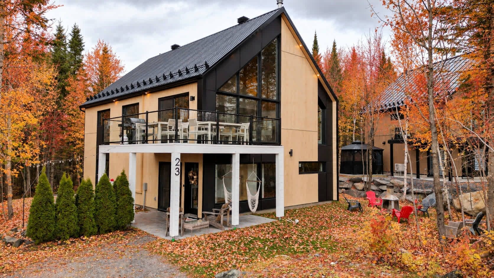 A modern two-story building with a balcony, surrounded by autumn foliage.