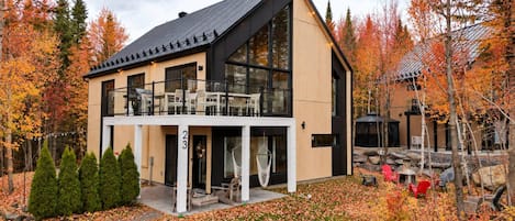 A modern two-story building with a balcony, surrounded by autumn foliage.