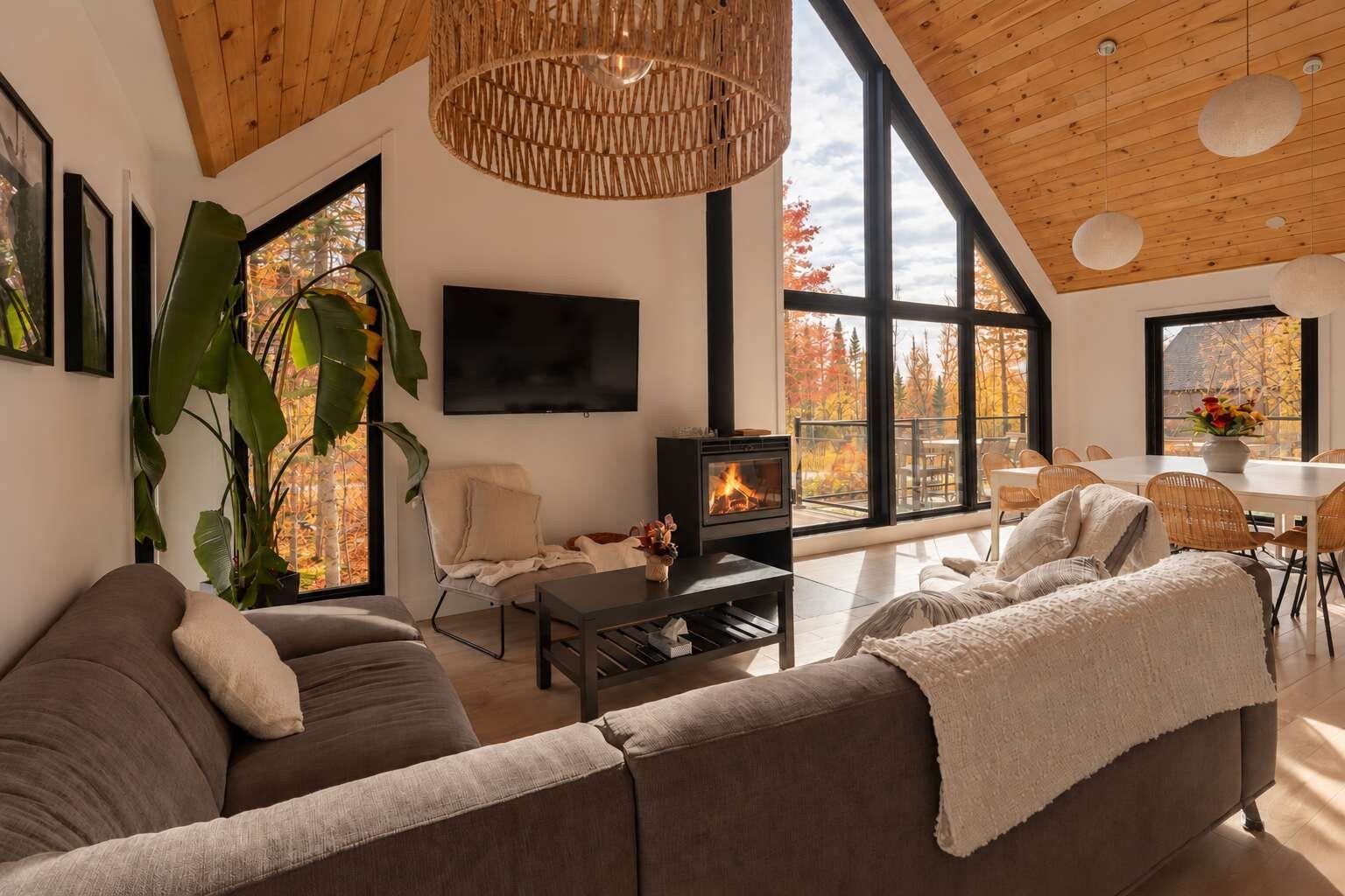 A modern living room with a fireplace, large windows, and a dining area.