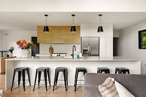 Cozinha moderna com ilha central, banquetas e iluminação pendente.