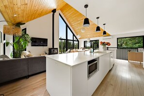 Une cuisine moderne dotée d’un grand îlot central, d’un plafond en bois et de grandes fenêtres.