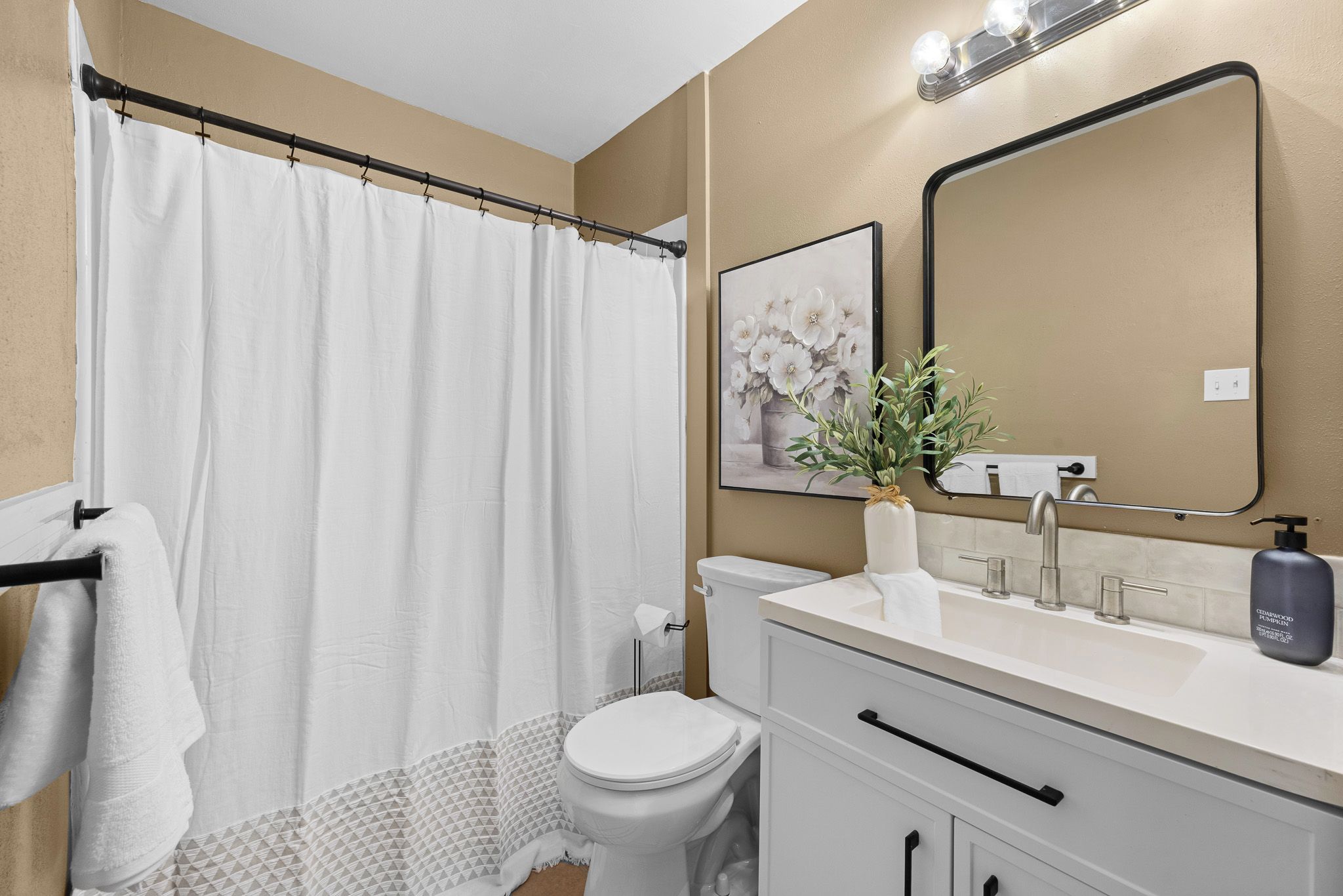A bathroom with a toilet, sink, mirror, and shower curtain.