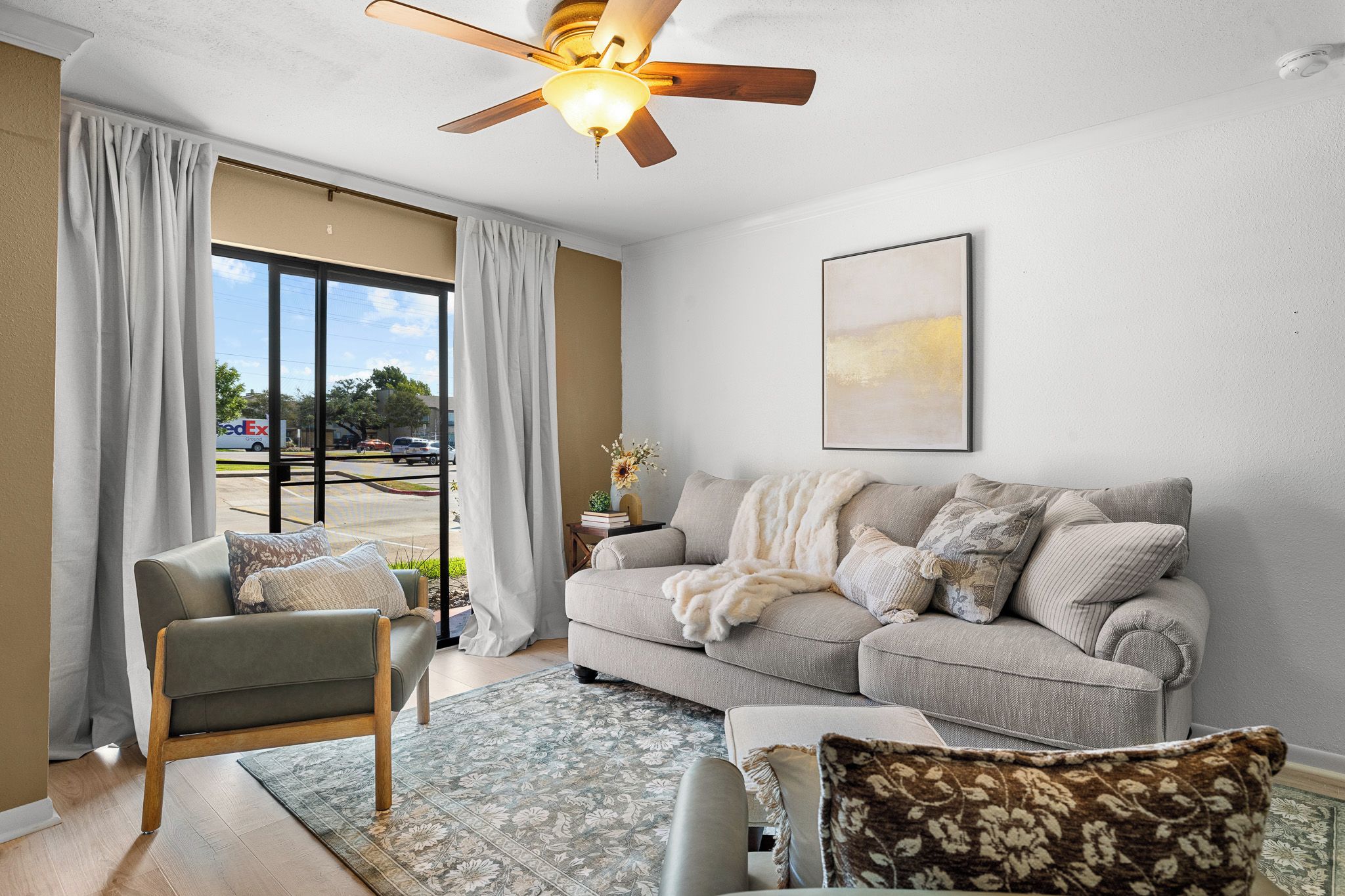 A living room with a sofa, armchair, and a ceiling fan.