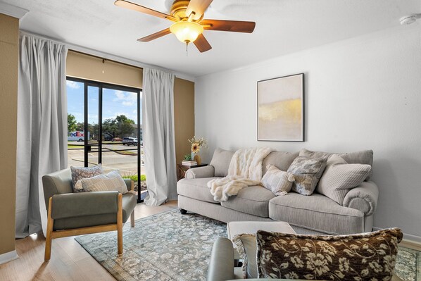A living room with a sofa, armchair, and a ceiling fan. - Cozy 2BR/2BA near TAMU w/ Pool & Washer (College Station)