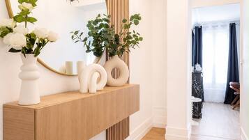 Un couloir avec une console en bois, un grand miroir et un lustre.